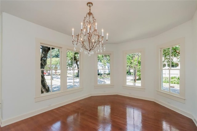 unfurnished dining area with dark hardwood / wood-style floors, a notable chandelier, and a healthy amount of sunlight