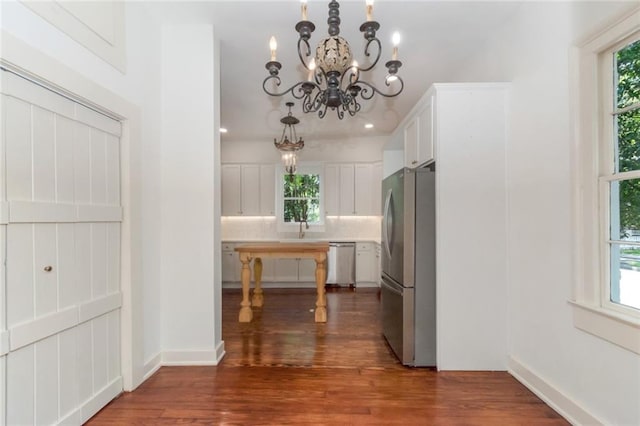 kitchen featuring backsplash, dark hardwood / wood-style flooring, a chandelier, stainless steel appliances, and white cabinets