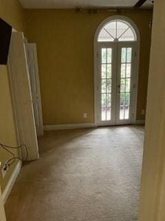 unfurnished room featuring baseboards, carpet floors, a healthy amount of sunlight, and french doors