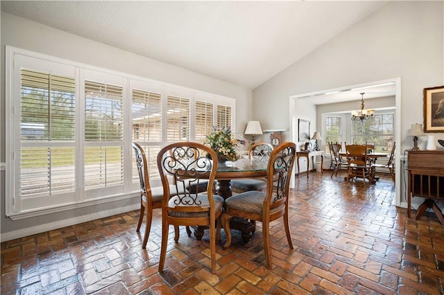 dining room with brick floor, baseboards, high vaulted ceiling, and an inviting chandelier