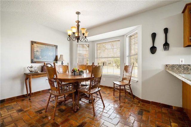 dining area featuring brick floor, baseboards, a textured ceiling, and an inviting chandelier