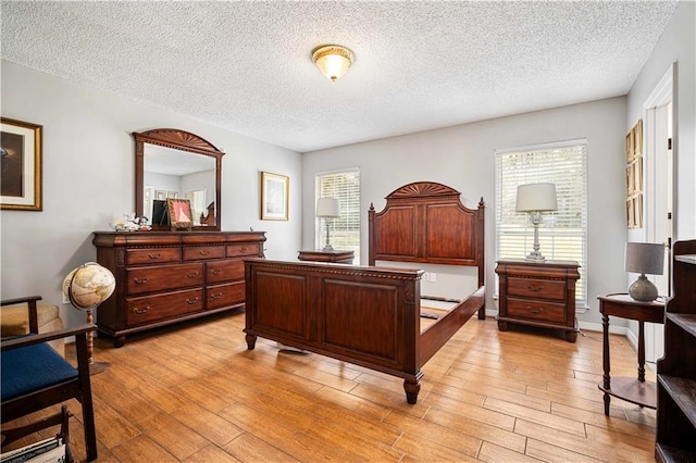 bedroom featuring light wood-style flooring, a textured ceiling, and baseboards