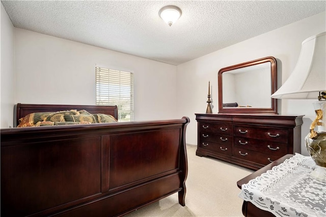 bedroom with light colored carpet and a textured ceiling