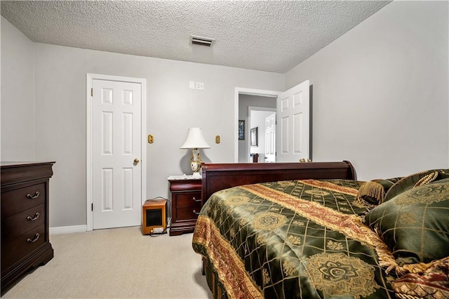 bedroom featuring visible vents, light colored carpet, a textured ceiling, and baseboards