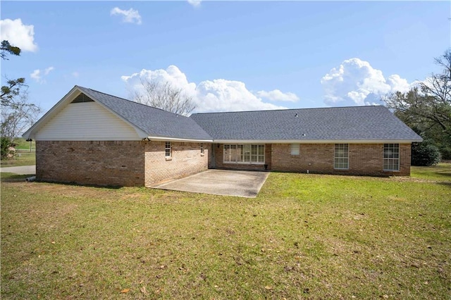 back of house featuring a yard, a patio, brick siding, and roof with shingles