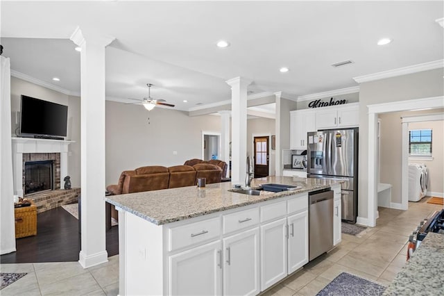 kitchen with stainless steel appliances, separate washer and dryer, a sink, a ceiling fan, and ornate columns