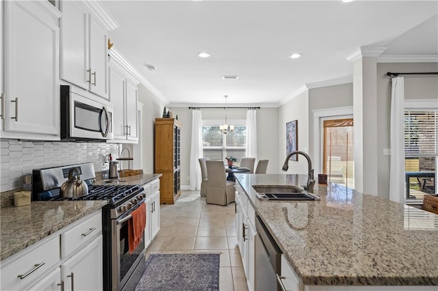 kitchen with a kitchen island with sink, a sink, white cabinetry, ornamental molding, and appliances with stainless steel finishes