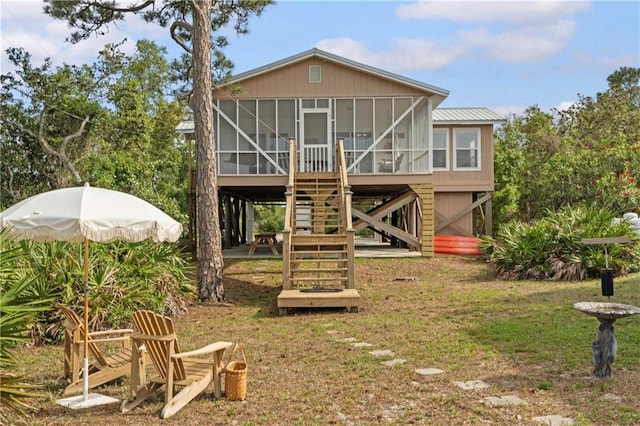 back of property with a sunroom, stairs, and a yard