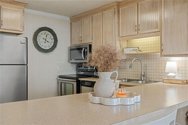 kitchen featuring appliances with stainless steel finishes, a sink, light brown cabinetry, crown molding, and light countertops
