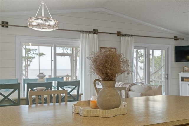 dining room with vaulted ceiling, ornamental molding, and wooden walls