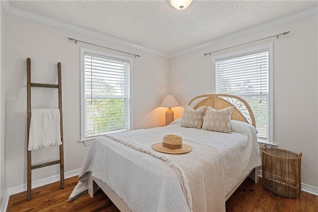 bedroom featuring wood finished floors, crown molding, a textured ceiling, and baseboards