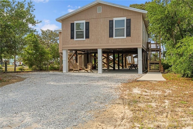 view of front of home featuring a carport, stairway, and gravel driveway