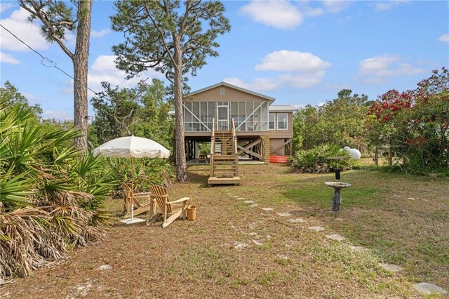 rear view of house featuring a sunroom, stairway, and a yard