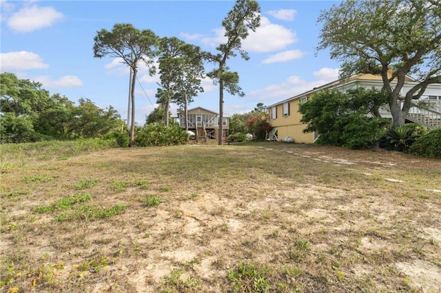 view of grassy yard with stairway and a wooden deck