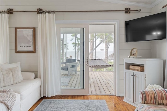 doorway to outside with light wood finished floors, crown molding, and vaulted ceiling