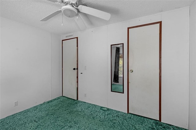 unfurnished room with a textured ceiling, carpet, visible vents, and a ceiling fan