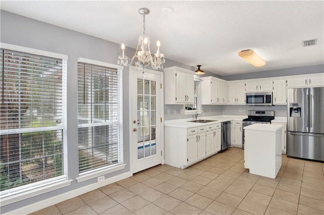 kitchen featuring white cabinetry, sink, hanging light fixtures, a center island, and stainless steel appliances