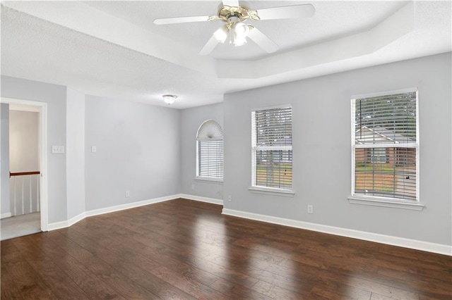 spare room featuring ceiling fan, dark hardwood / wood-style flooring, and a tray ceiling