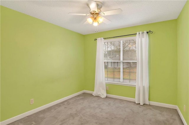 spare room featuring a textured ceiling, light colored carpet, and ceiling fan