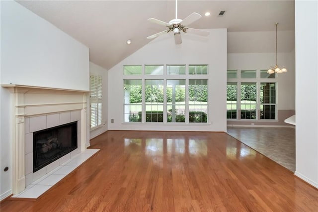 1056 Cross Gates Pl, Mobile, AL 36609 - unfurnished living room with a tiled fireplace, high vaulted ceiling, a chandelier, ceiling fan, and wood finished floors