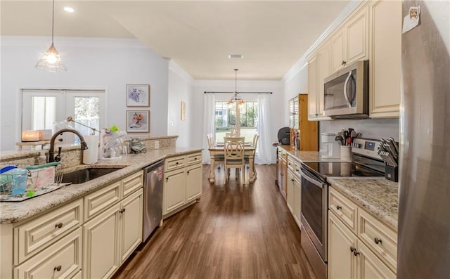 kitchen featuring cream cabinetry, appliances with stainless steel finishes, pendant lighting, and sink