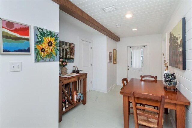 dining space featuring beamed ceiling and concrete flooring