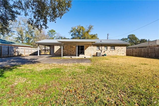 back of house featuring metal roof, fence private yard, central air condition unit, brick siding, and a lawn