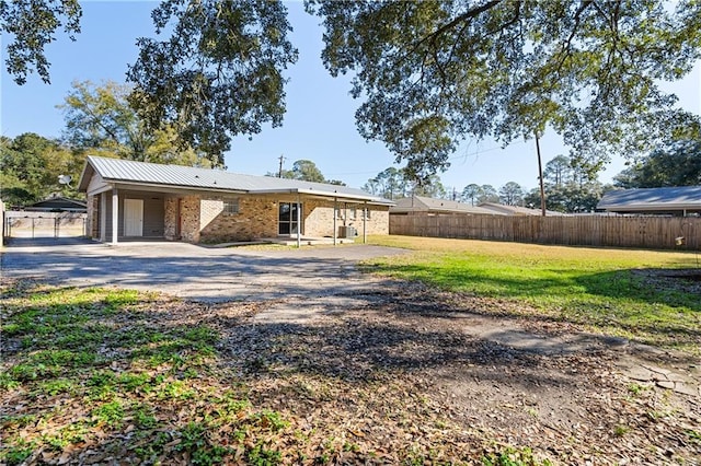 view of front of property featuring brick siding, metal roof, fence, driveway, and a front lawn