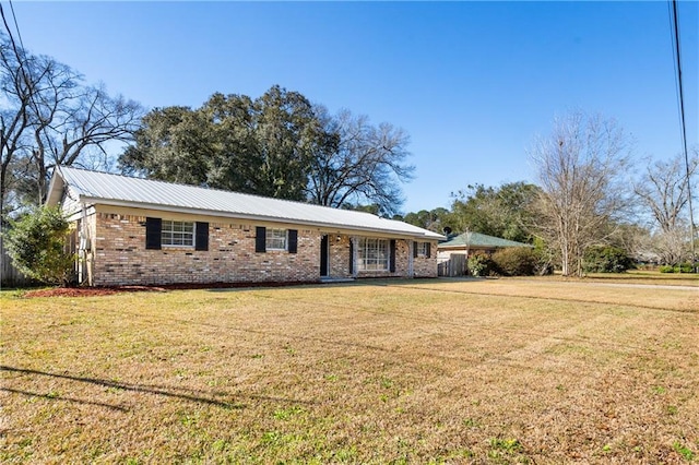 ranch-style house with metal roof, brick siding, and a front yard