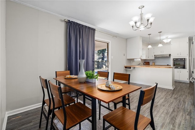 dining room with a chandelier, dark wood-style flooring, and baseboards