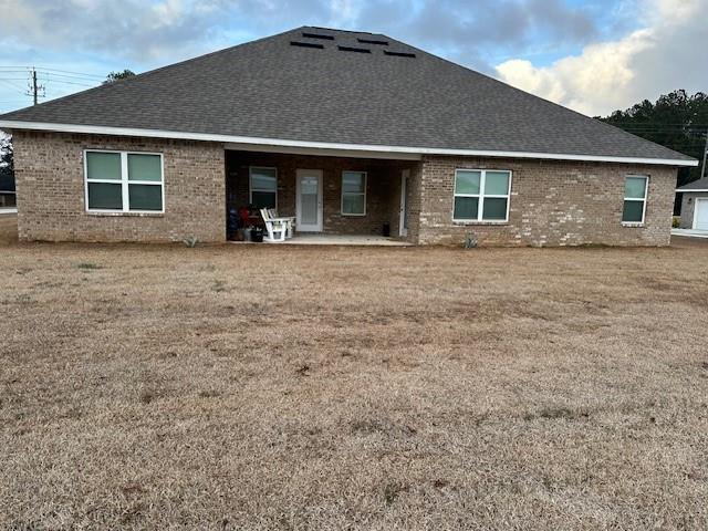 back of property with a yard and a patio area