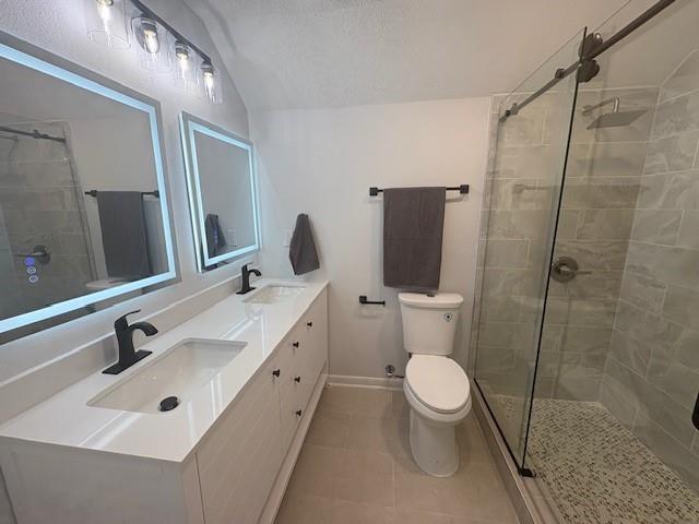 709 Oak Field Dr, Mobile, AL 36609 - full bathroom with toilet, double vanity, a tile shower, vaulted ceiling, and tile patterned floors