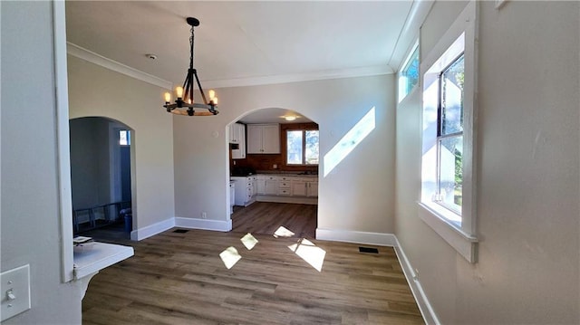 unfurnished dining area with ornamental molding, a notable chandelier, and dark hardwood / wood-style floors