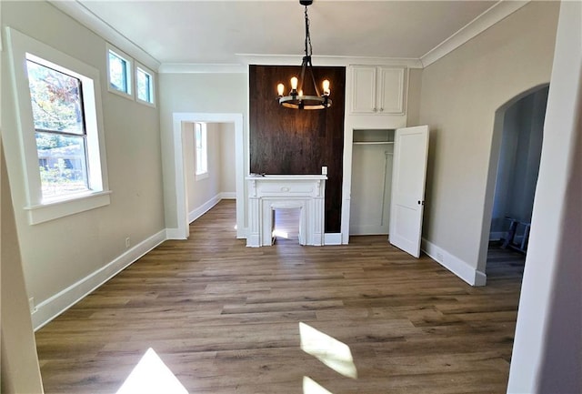 unfurnished living room with an inviting chandelier, ornamental molding, and wood-type flooring