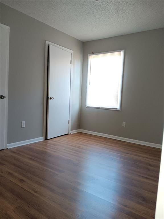 empty room with dark hardwood / wood-style floors and a textured ceiling