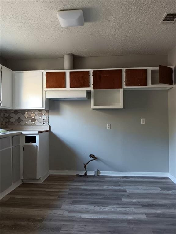 kitchen featuring white cabinetry, a textured ceiling, tasteful backsplash, and dark wood-type flooring