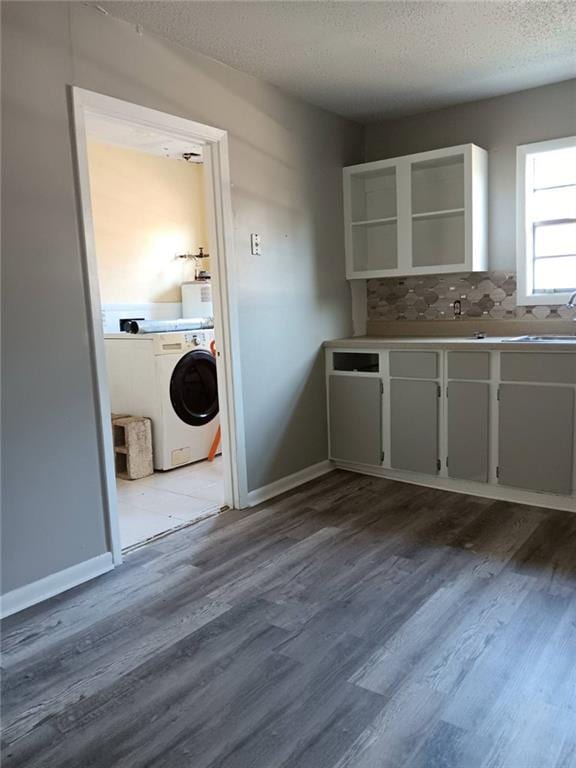 clothes washing area with sink, a textured ceiling, wood-type flooring, and washer / clothes dryer