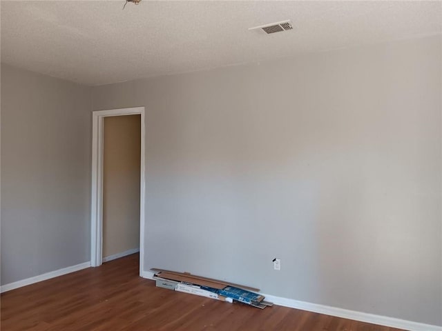 spare room featuring a textured ceiling and hardwood / wood-style flooring