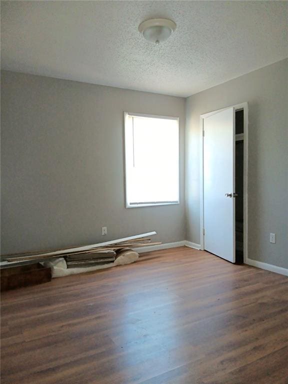 unfurnished room with a textured ceiling and hardwood / wood-style flooring