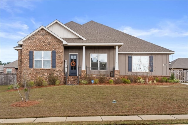 view of front of home with a front yard, brick siding, board and batten siding, and roof with shingles