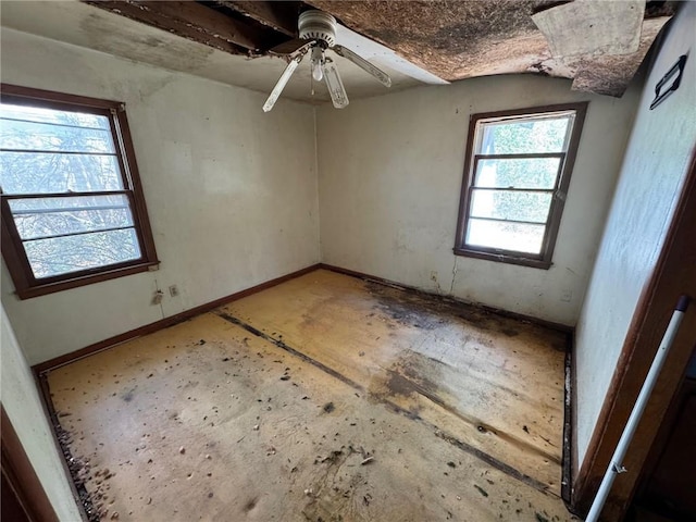 spare room with a ceiling fan and baseboards