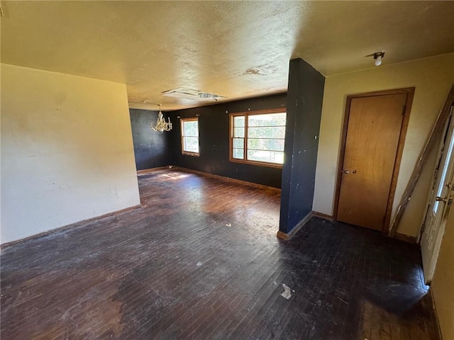 empty room featuring a notable chandelier, baseboards, and hardwood / wood-style flooring