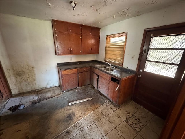 kitchen featuring dark countertops, brown cabinetry, and a sink