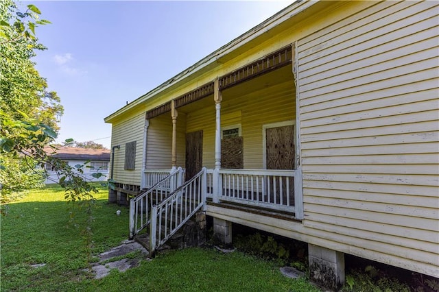 property entrance featuring a lawn and covered porch
