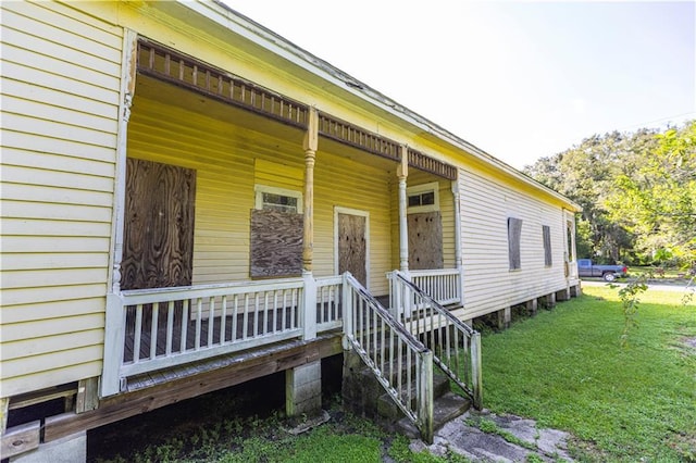 entrance to property with a porch and a yard