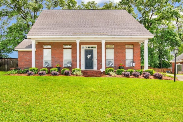view of front facade with a shingled roof, a front lawn, and fence
