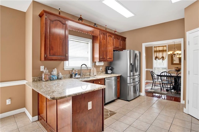 kitchen with a peninsula, light tile patterned flooring, plenty of natural light, a sink, and appliances with stainless steel finishes