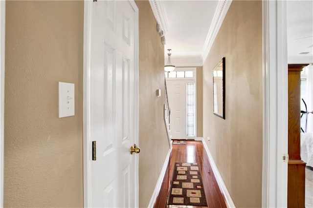 corridor with crown molding, dark wood-style flooring, a textured wall, and baseboards