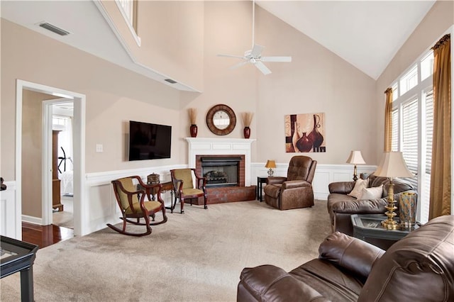 living room featuring visible vents, carpet, wainscoting, and ceiling fan