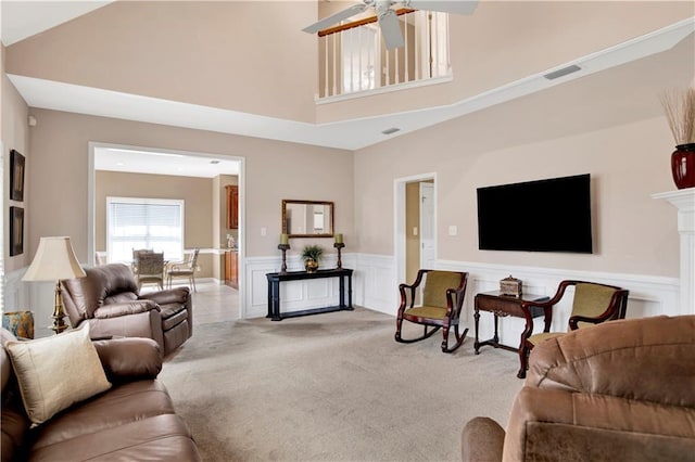 living room with visible vents, carpet flooring, wainscoting, and ceiling fan